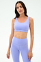 A woman stands against a plain backdrop wearing the SPLITS59 Sprint Rigor Bra in Purple Haze, styled for multi-sport performance and ideal for gym workouts.