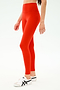 A person wearing SPLITS59 Sprint High Waist Rigor 7/8 leggings in Lotus Red and white athletic shoes with black stripes, standing against a plain light background.