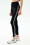 Wearing SPLITS59 Amber Airweight High Waist 7/8 leggings in Black/White with side stripes and white sneakers—ideal for hot yoga or casual wear against a plain backdrop.