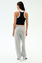 A woman faces away, wearing the SPLITS59 Kiki Rib Crop Tank in Black/White with light gray sweatpants and white sneakers, set against a plain white background.