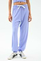 A person models the SPLITS59 Andie Oversized Fleece Sweatpant in Purple Haze—featuring a white drawstring and styled with silver sneakers—against a plain white background, ideal for warm weather workouts.