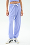 A person models the SPLITS59 Andie Oversized Fleece Sweatpant in Purple Haze—featuring a white drawstring and styled with silver sneakers—against a plain white background, ideal for warm weather workouts.