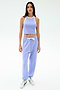A person stands facing forward in the SPLITS59 Andie Oversized Fleece Sweatpant in Purple Haze, styled with a lavender crop top and white sneakers—an ideal outfit for warm weather workouts.