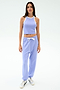 A person stands facing forward in the SPLITS59 Andie Oversized Fleece Sweatpant in Purple Haze, styled with a lavender crop top and white sneakers—an ideal outfit for warm weather workouts.