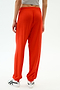 A person wears the SPLITS59 Andie Oversized Fleece Sweatpant in Lotus Red with a gray crop top and white athletic shoes, standing against a plain light background—a vibrant, comfortable choice for warm weather workouts.