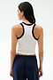 A woman faces away, wearing the SPLITS59 Kiki Rib Crop Tank in White/Indigo with navy pants against a light background—ideal for gym workouts.