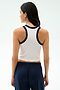 A woman faces away, wearing the SPLITS59 Kiki Rib Crop Tank in White/Indigo with navy pants against a light background—ideal for gym workouts.