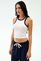 A woman wears the SPLITS59 Kiki Rib Crop Tank in White/Indigo, featuring a baby rib fabric and indigo trim—ideal for gym sessions or casual looks—while standing against a plain light background.