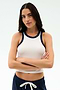 A woman with long brown hair stands with arms crossed, wearing the SPLITS59 Kiki Rib Crop Tank in White/Indigo and navy drawstring shorts against a plain background.