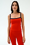 A woman faces the camera in a SPLITS59 Monah Rigor Tank - Lotus Red/Indigo and matching red pants, both crafted from soft Rigor fabric, set against a plain light background.