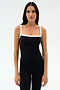 A woman with long dark hair wears the SPLITS59 Monah Rigor Tank in Black/White—an ideal sleeveless top for gym workouts—paired with matching black pants, standing against a plain white background.