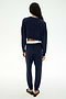 Wearing the SPLITS59 Andie Dual Waist Sweatpant in Indigo/White, this person—proudly made in Los Angeles—stands with their back to the camera, styled with a navy blue long-sleeve top, black flats, and a visible white waistband crafted from ultra-luxe fleece.