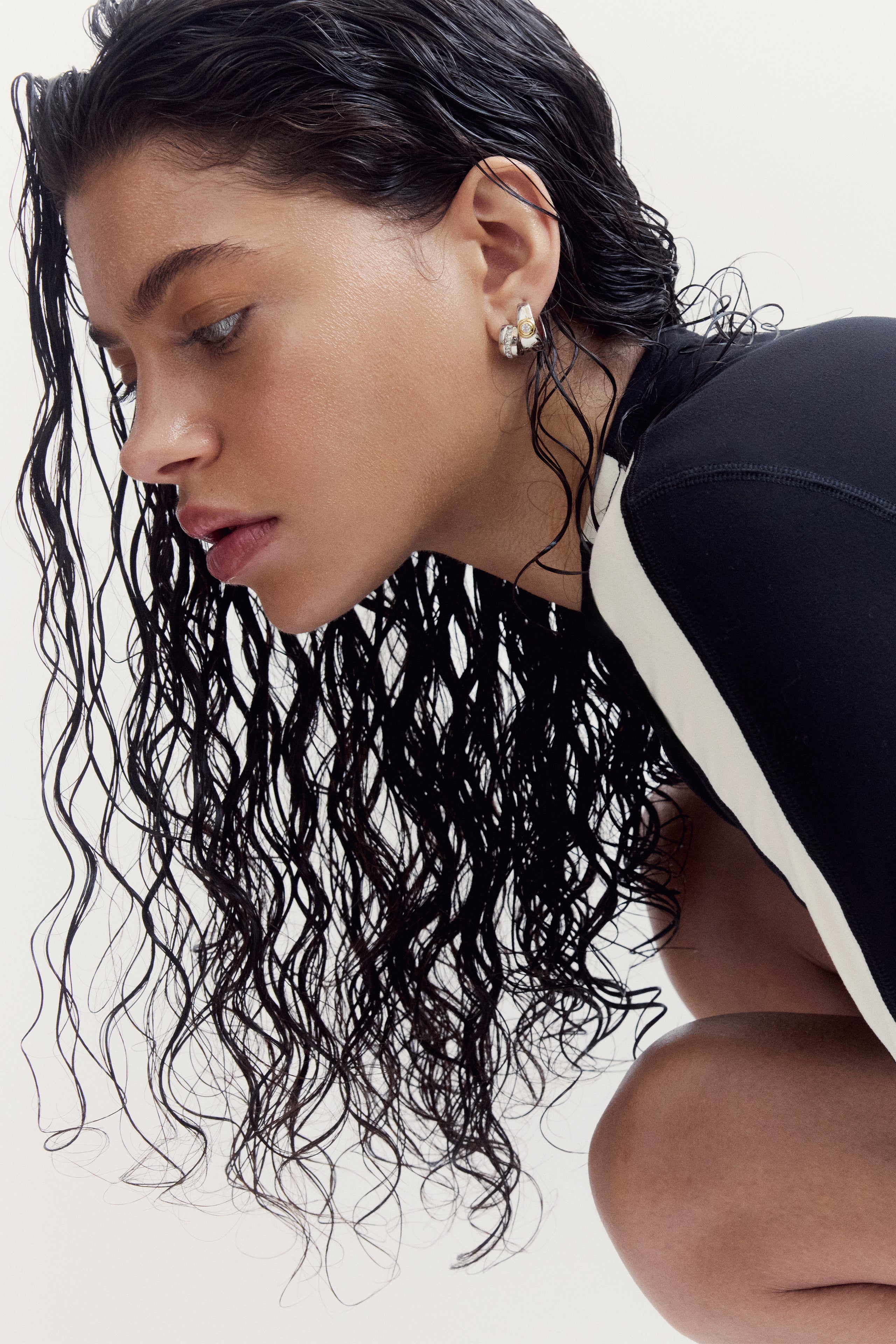 A person with wet hair wears a black and white The Soho Set athletic top while leaning forward.
