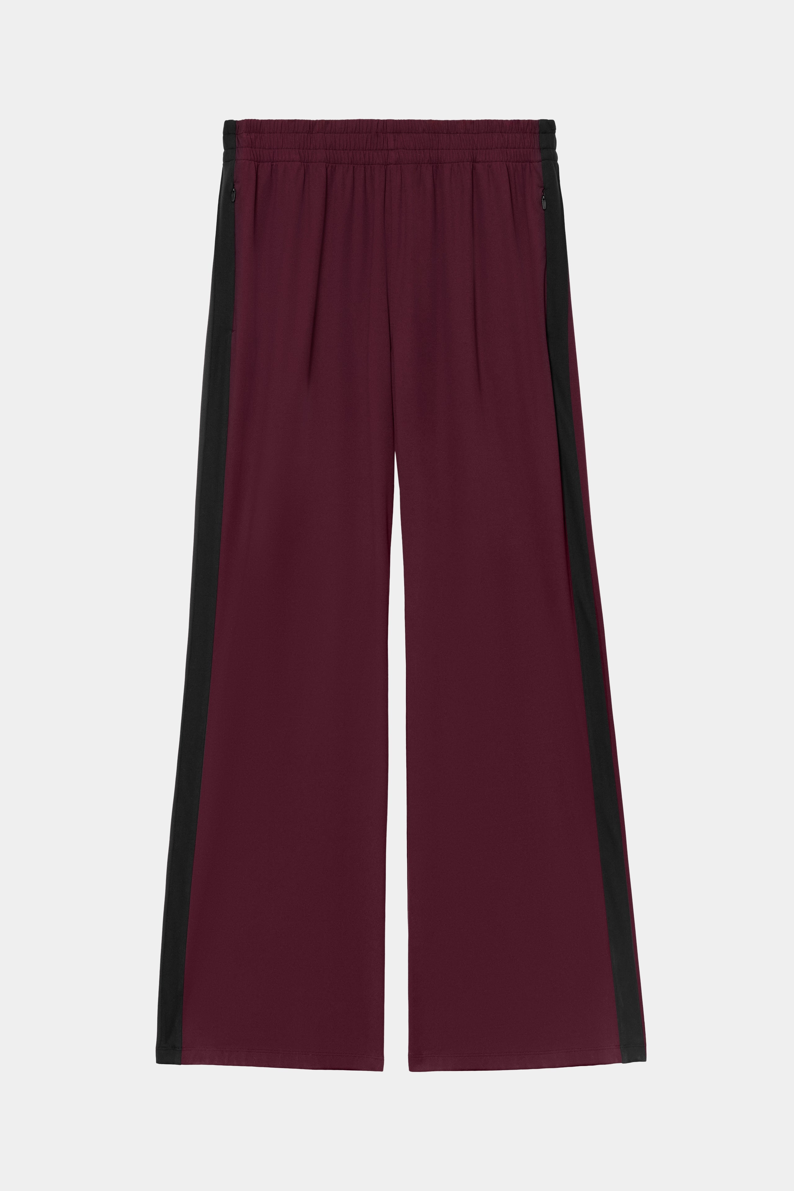 The SPLITS59 Maxie Rigor Track Pant in Dark Cherry and Black features wide-leg styling, black side panels, and an elastic waistband, crafted from a comfortable nylon-spandex blend. The pants are displayed against a plain white background.