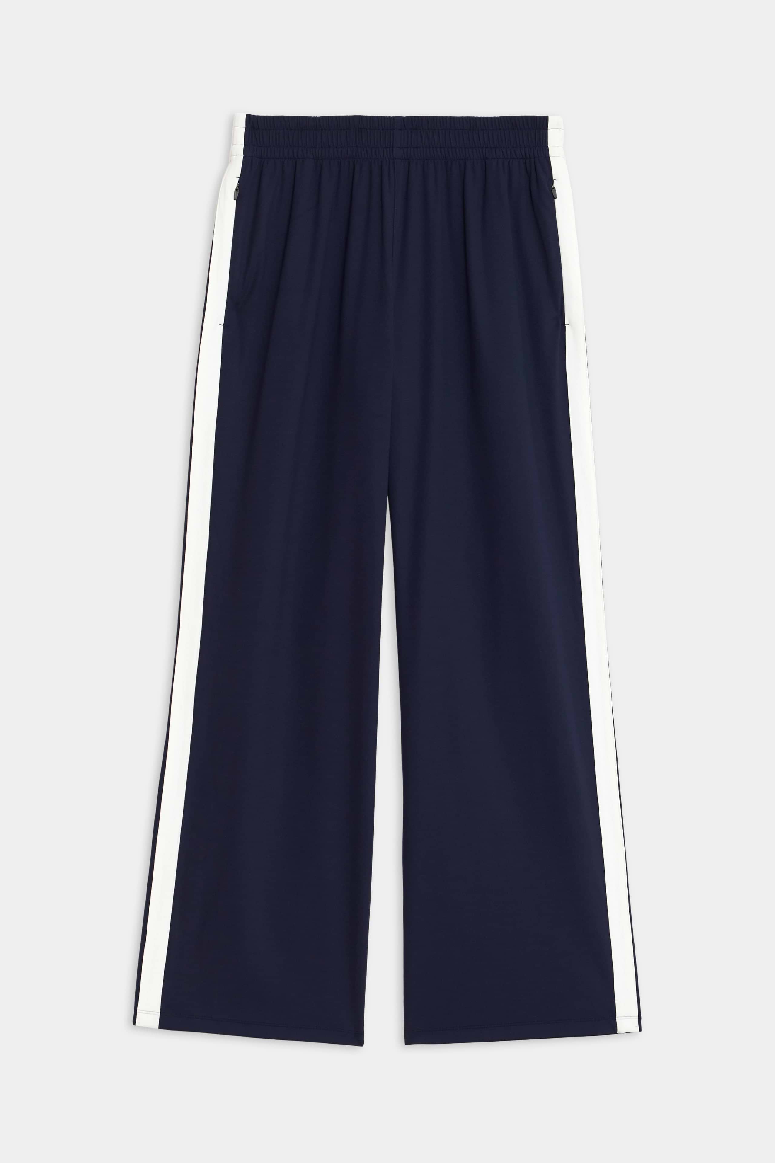 Maxie Rigor Track Pant by SPLITS59, featuring a navy color with an elastic waistband and white side stripes, showcased on a plain background.