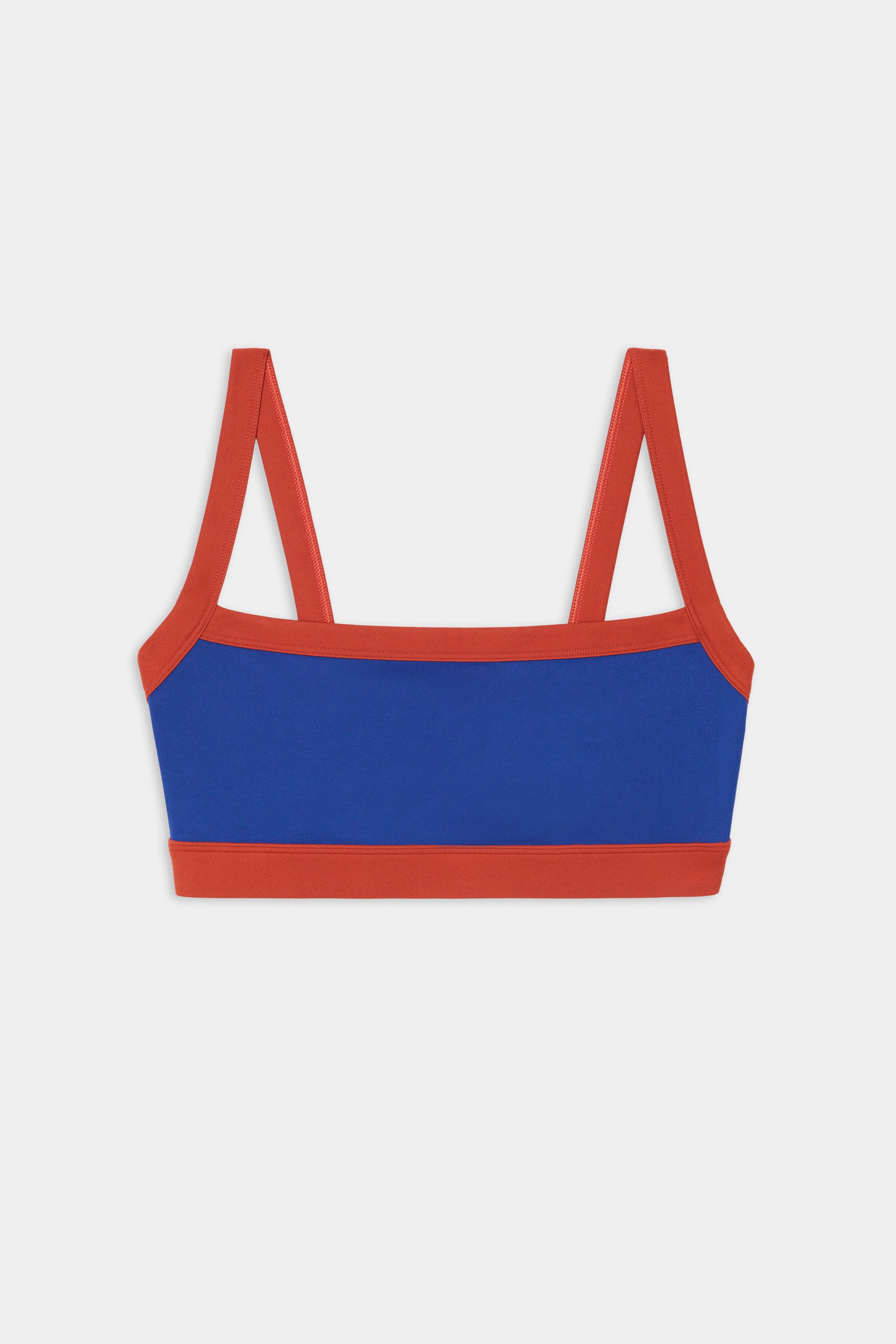 The Monah Rigor Bra - Cobalt/Terracotta by SPLITS59 features blue nylon spandex, wide red straps, and red trim, shown against a white background.
