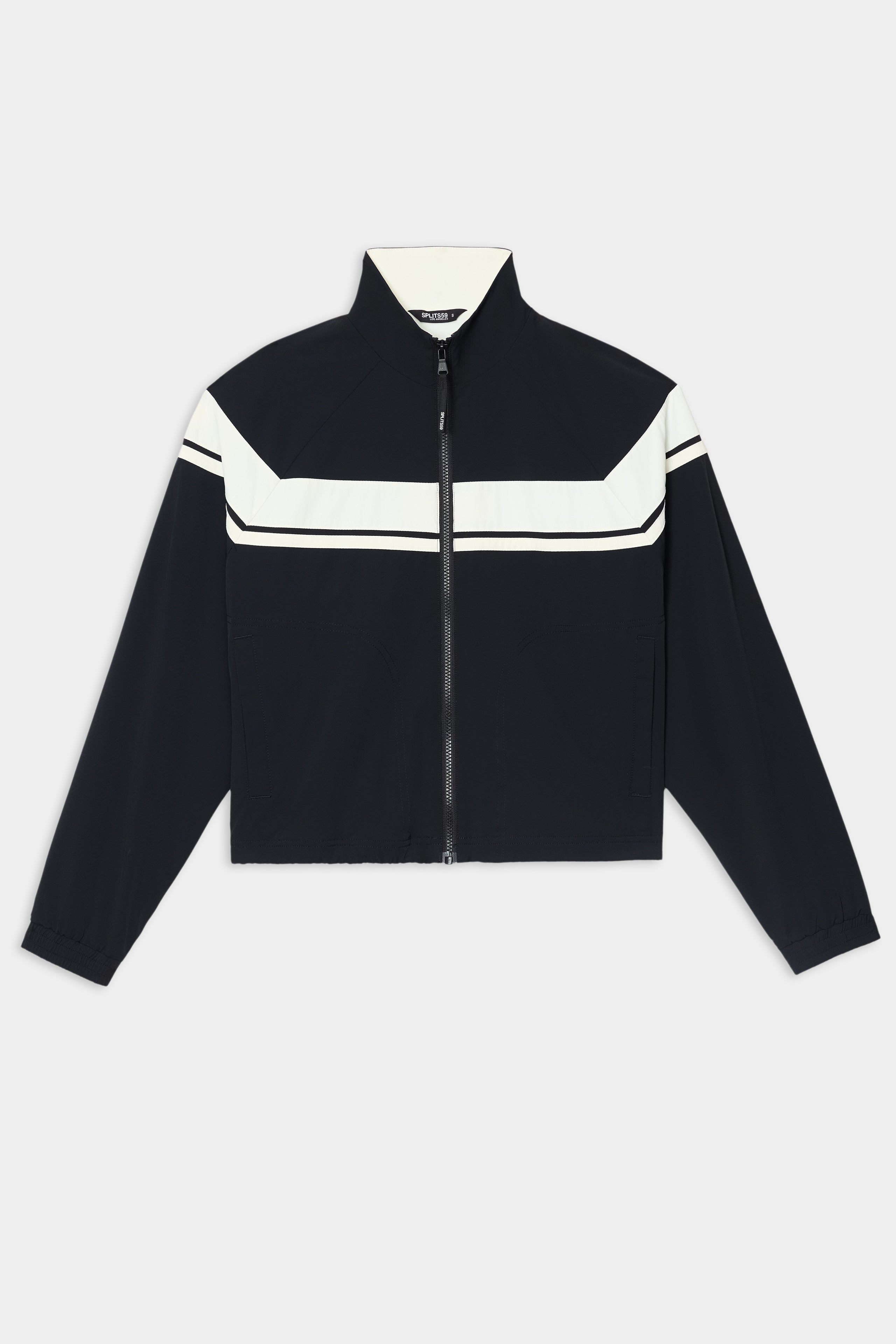 The SPLITS59 Morrison Nylon Twill Track Jacket in Black/Creme is crafted from a comfortable nylon-spandex blend and features a striking white chevron stripe across the chest and shoulders, long sleeves, and a high collar, displayed laid flat on a white background.
