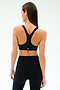 A woman with straight brown hair is seen from behind, wearing the SPLITS59 Ella Airweight Bra in Black/Classic Blue and high-waisted black leggings, both crafted from sleek nylon spandex, set against a plain light background.