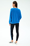 A woman stands facing away, wearing the SPLITS59 Andie Oversize Fleece Sweatshirt in Classic Blue with black leggings featuring a blue stripe, paired with white sneakers against a plain white background.