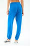A person is shown from the back in SPLITS59's Andie Oversized Fleece Sweatpant in Classic Blue, paired with white sneakers, against a plain white background.