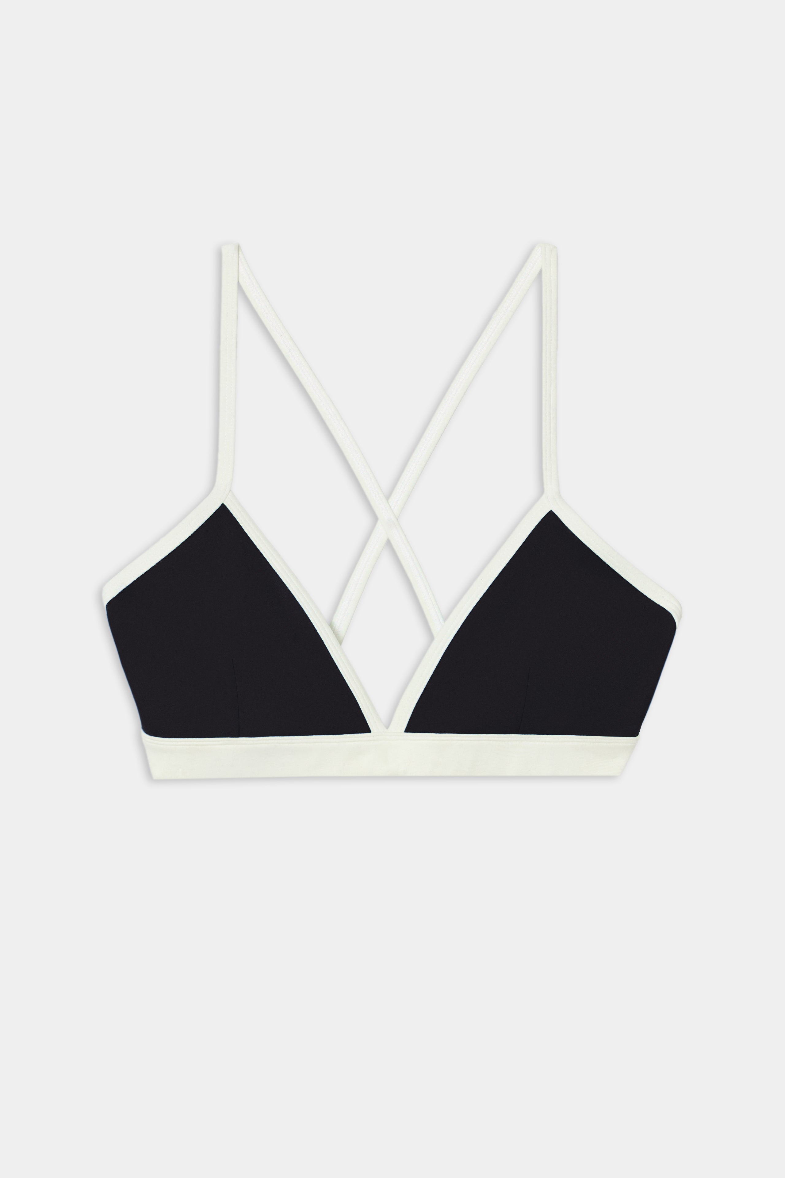 The SPLITS59 Sage Rigor Bra in Black/White is crafted from a soft nylon-spandex blend, featuring thin double straps that cross at the back and white trim, displayed on a white background.