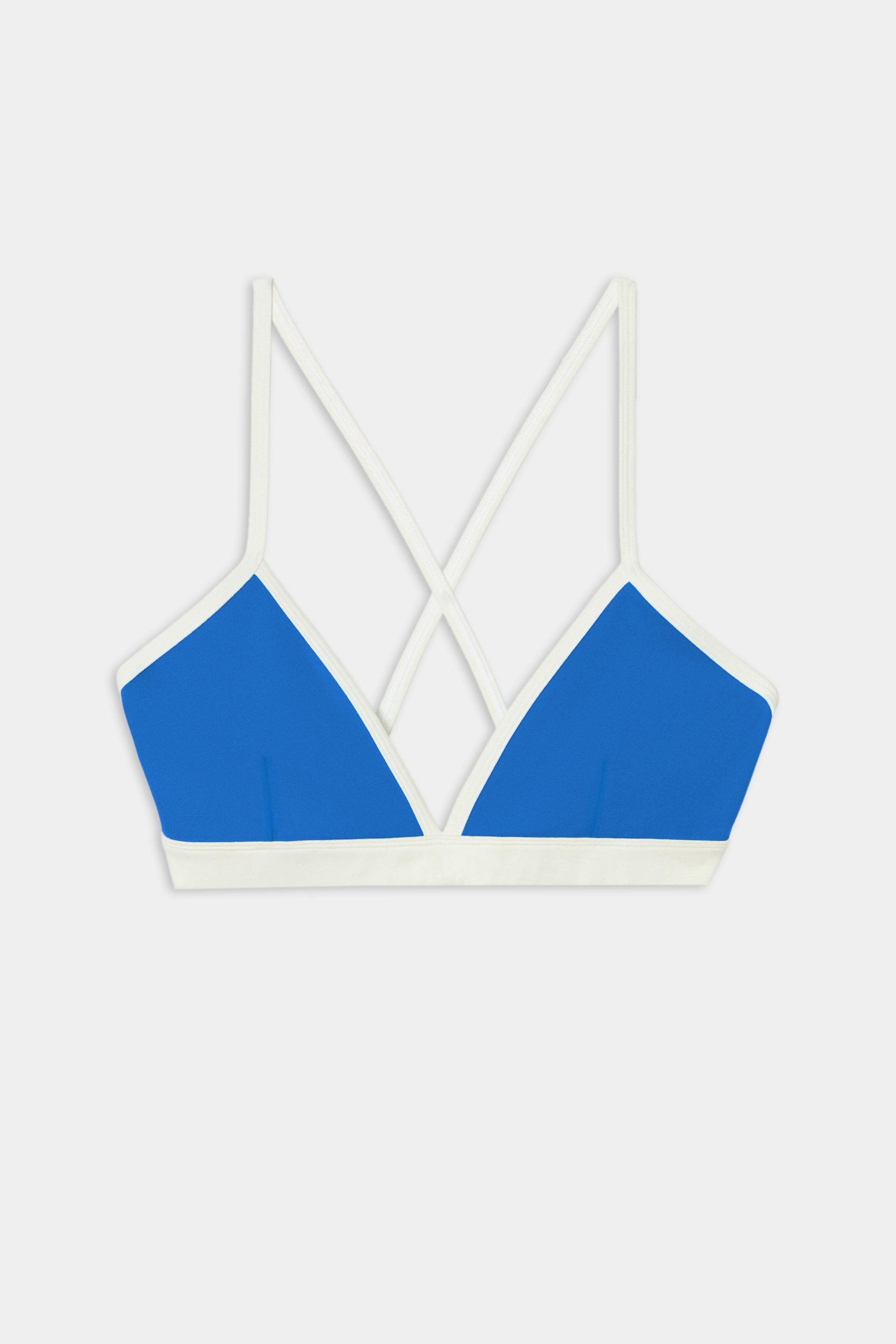 SPLITS59 Sage Rigor Bra in Classic Blue/White, a bralette-style top crafted from soft nylon spandex fabric, features white straps and trim with a crisscross back design, showcased against a plain white background.