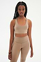 Front view of woman with black braids wearing light brown leggings and light brown bra