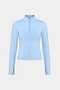 The SPLITS59 Tess Rigor Half Zip Waist Length in Skylight is a women's light blue long-sleeve top with a mock neck and front half-zip, made from a soft nylon-spandex blend, shown against a plain white background.