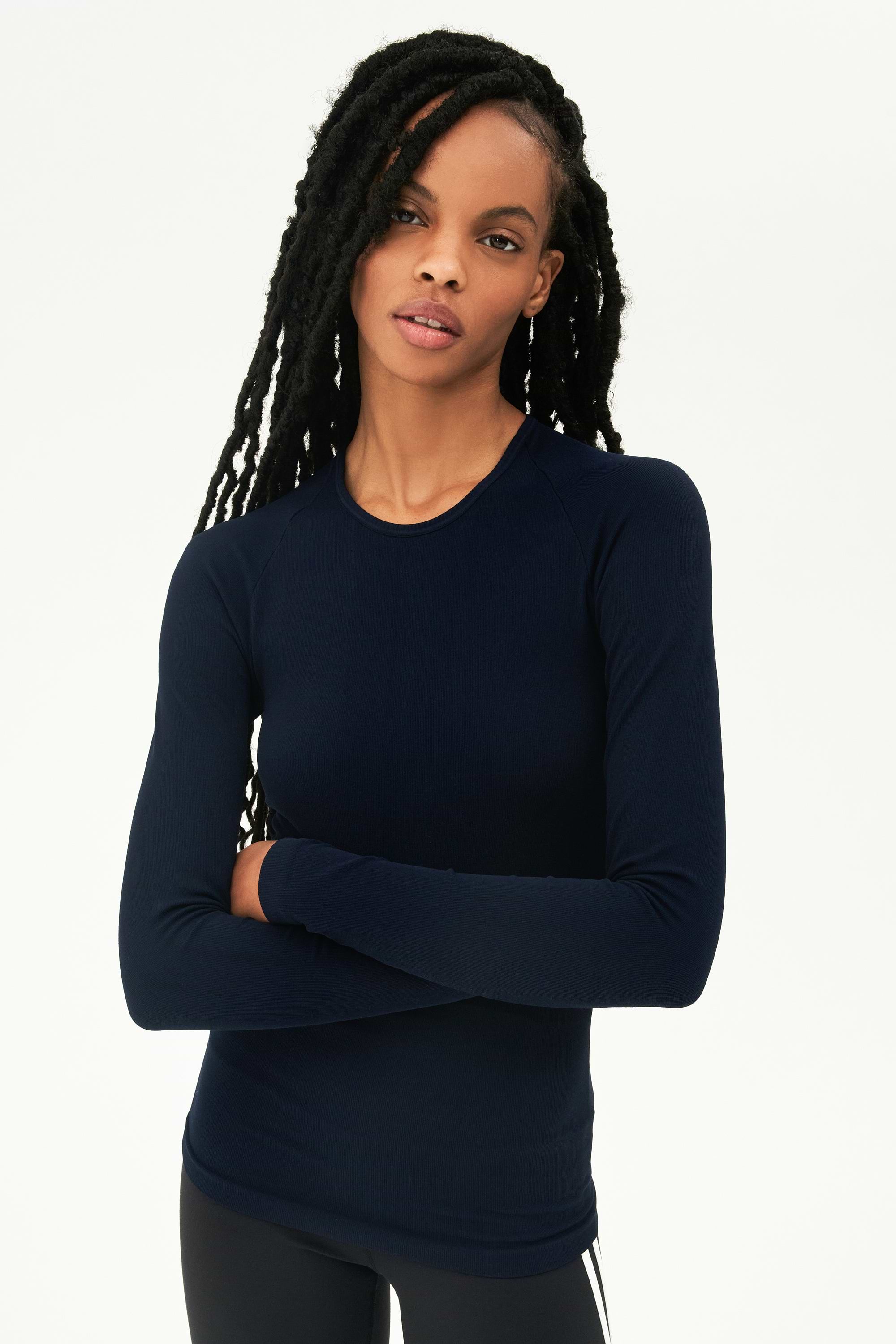 A woman wearing a Loren Seamless L/S Tee in Indigo and black leggings designed from seamless fabric, perfect for gym workouts by SPLITS59.
