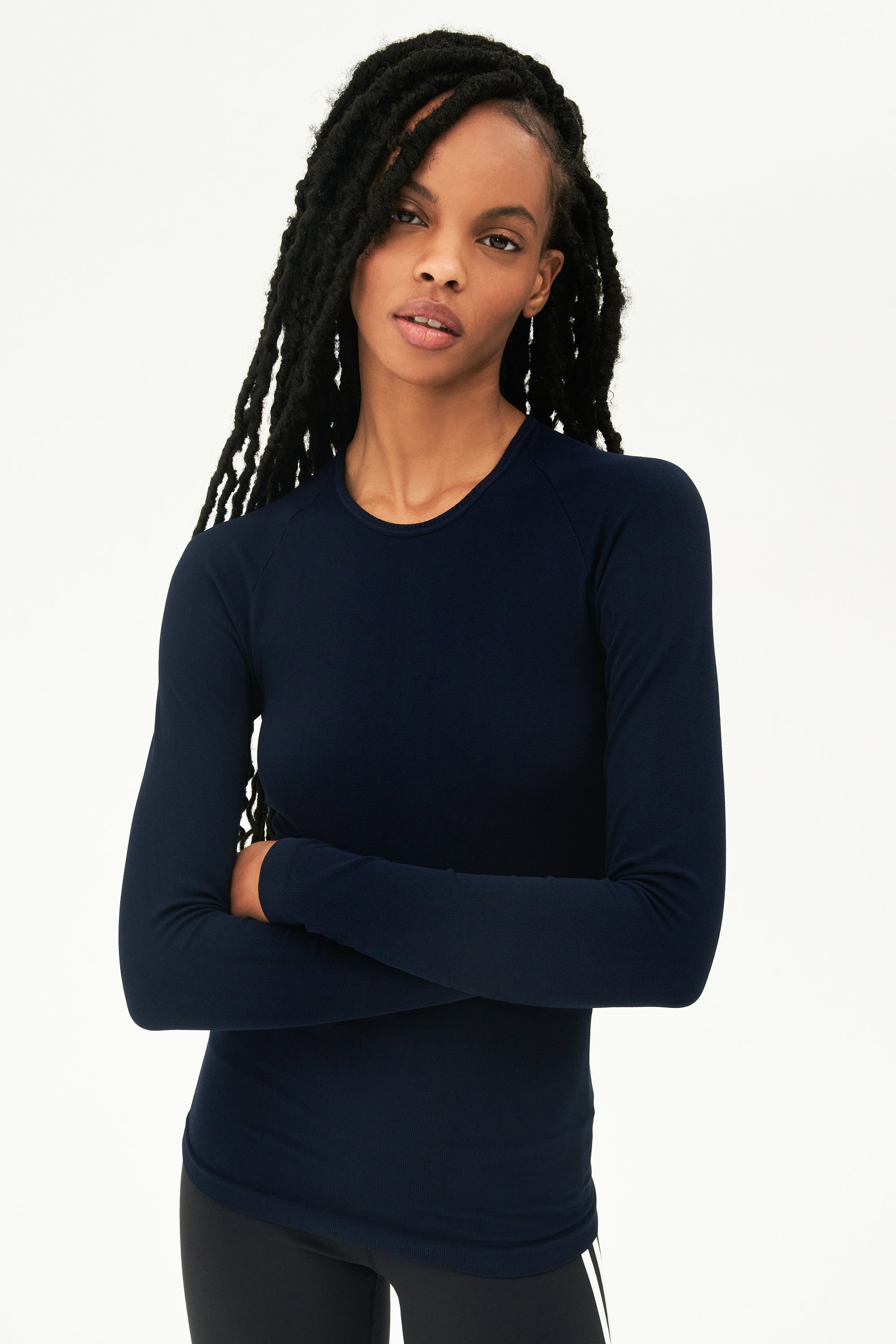 A woman wearing a Loren Seamless L/S Tee in Indigo and black leggings designed from seamless fabric, perfect for gym workouts by SPLITS59.