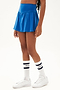 Side view of girl wearing blue upper thigh skirt with built in shorts and white shoes