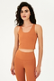 Front view of woman with curly dark brown hair wearing a dark orange bra tank with dark orange leggings