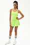 Full front view of girl wearing neon green upper thigh skirt with built in shorts, neon green tank top and white shoes