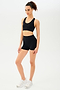 Full side view of girl wearing black shorts with black sports bra and white shoes