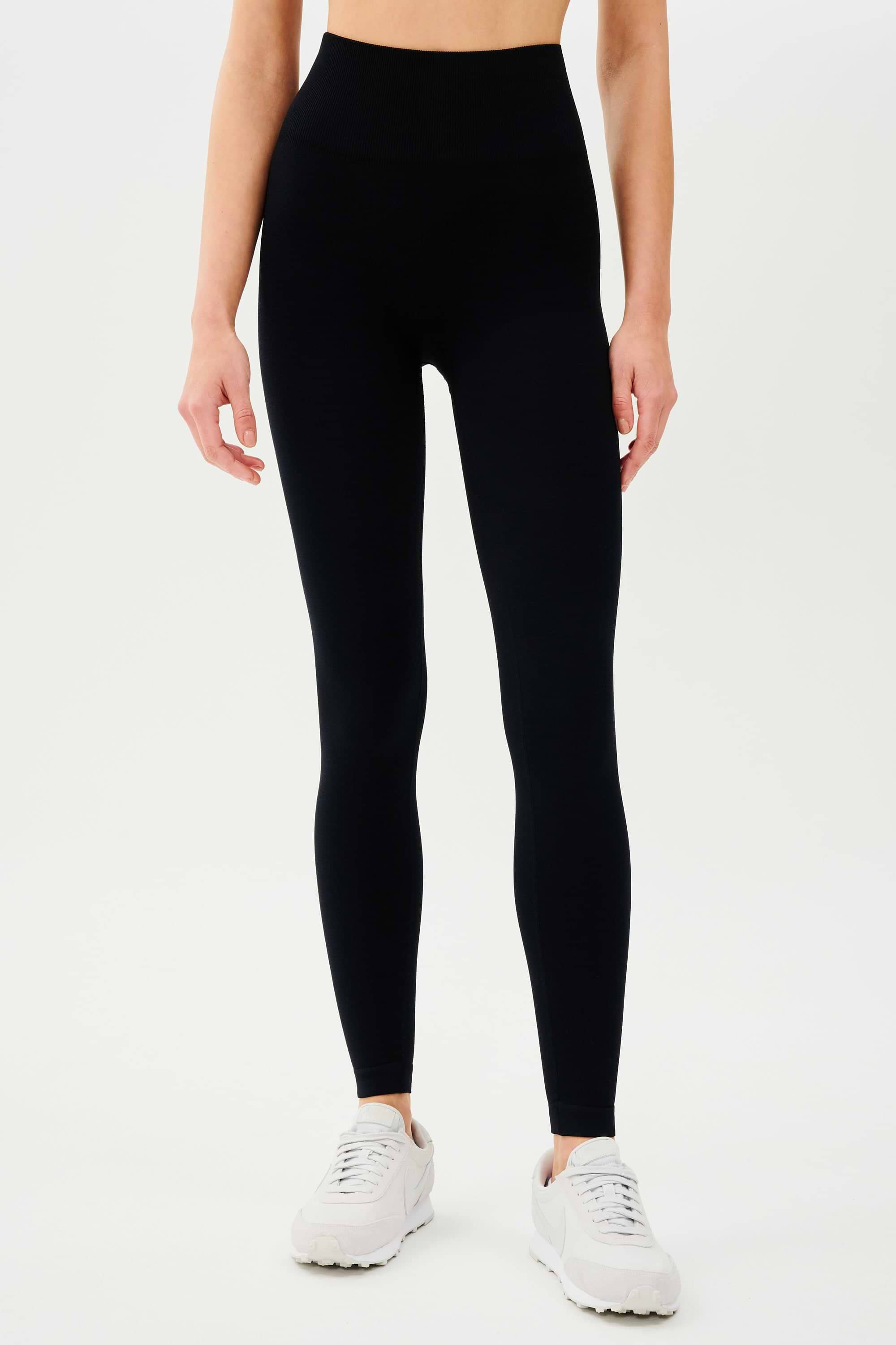 The back view of a woman wearing SPLITS59's Loren Seamless High Waist Full Length - Black leggings.