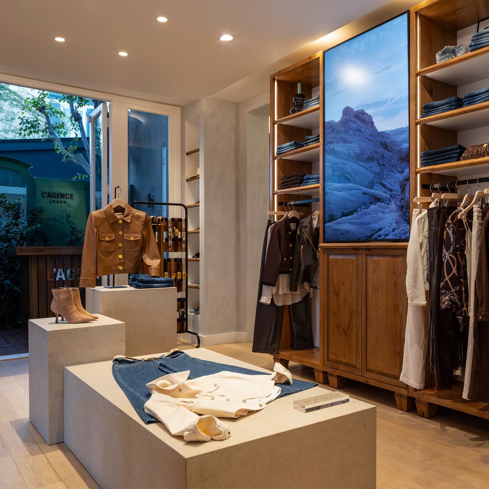 Interno di un negozio di abbigliamento con scaffali in legno e tavoli espositivi.