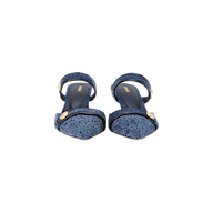 The Gilliane Denim Mule is a pair of blue denim open-toe sandals with ankle straps and embossed dome button details, featuring a memory foam cushion for added comfort, displayed on a white background.