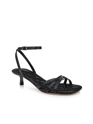 La sandale en cuir Genette est une sandale noire à talons bas, dotée de lanières, dune semelle intérieure matelassée et dune fine bride à la cheville ornée dune petite boucle, présentée sur fond blanc.