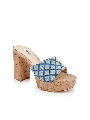 The Gabriell Platform Sandal is a high-heeled denim sandal with a cork block heel, blue and white crisscross fabric strap, and plush memory foam cushioning for comfort.