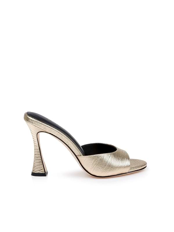 The Avery Leather Open-Toe Mule is shown in lizard-embossed gold leather with a sculpted stiletto mule silhouette, flared heel, and black insole, displayed against a white background.