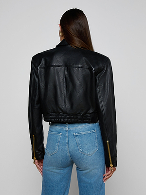 A person with long brown hair is shown from the back wearing the Micah Oversized Leather Jacket in black quilted leather and light blue jeans against a plain white background.