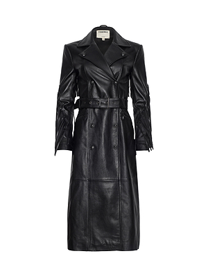 The Celina Fringed Leather Trench is a long black lambskin coat with a belted waist, double-breasted buttons, wide lapels, and seam detailing, displayed on a plain white background.