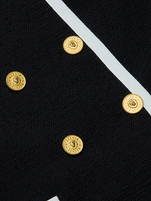 Close-up of the Mazikeen Tweed Jacket's black tweed fabric, showcasing four diagonally arranged gold embossed buttons and a white intersecting stripe.