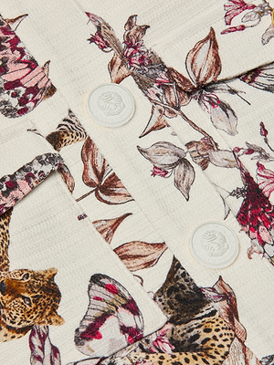A close-up of the Nyx Cropped Jacket in lightweight printed cotton, featuring butterflies, leopards, and leaves, finished with two shiny gold lion’s head embossed buttons.