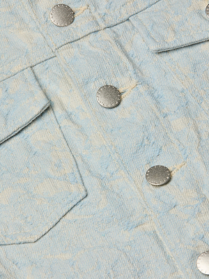 Close-up of the Maven Jacket, a light blue cotton jacquard piece with a structured fit, silver snap buttons, and flap pockets.