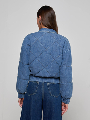 A person with long brown hair is shown from the back wearing the L'AGENCE Ryah Bomber Jacket and wide-leg blue jeans, set against a plain light gray background.