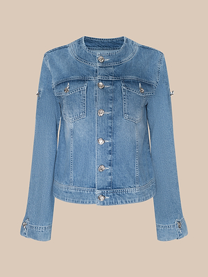 The Anouk Jean Jacket is a light blue, relaxed fit with long sleeves, silver front buttons, two chest flap pockets, and buttoned cuffs, shown on a beige background.