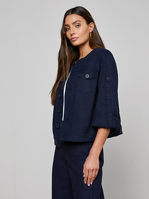 A woman with long brown hair wears the Anouk Jean Jacket, featuring rolled sleeves and a collarless design, paired with matching relaxed fit jeans against a plain light gray background.