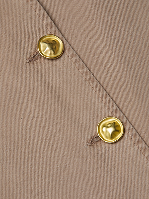 Close-up of two gold, hammered-texture buttons on light brown fabric with diagonal stitching, highlighting the refined detail of the Zavia Jean Trench Coat by L'AGENCE, featuring an oversized collar.