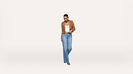 A woman stands against a plain white background, wearing a tan jacket, white top, light blue high-waisted jeans, and sandals. She is looking down, smiling, and has her hands in her pockets.